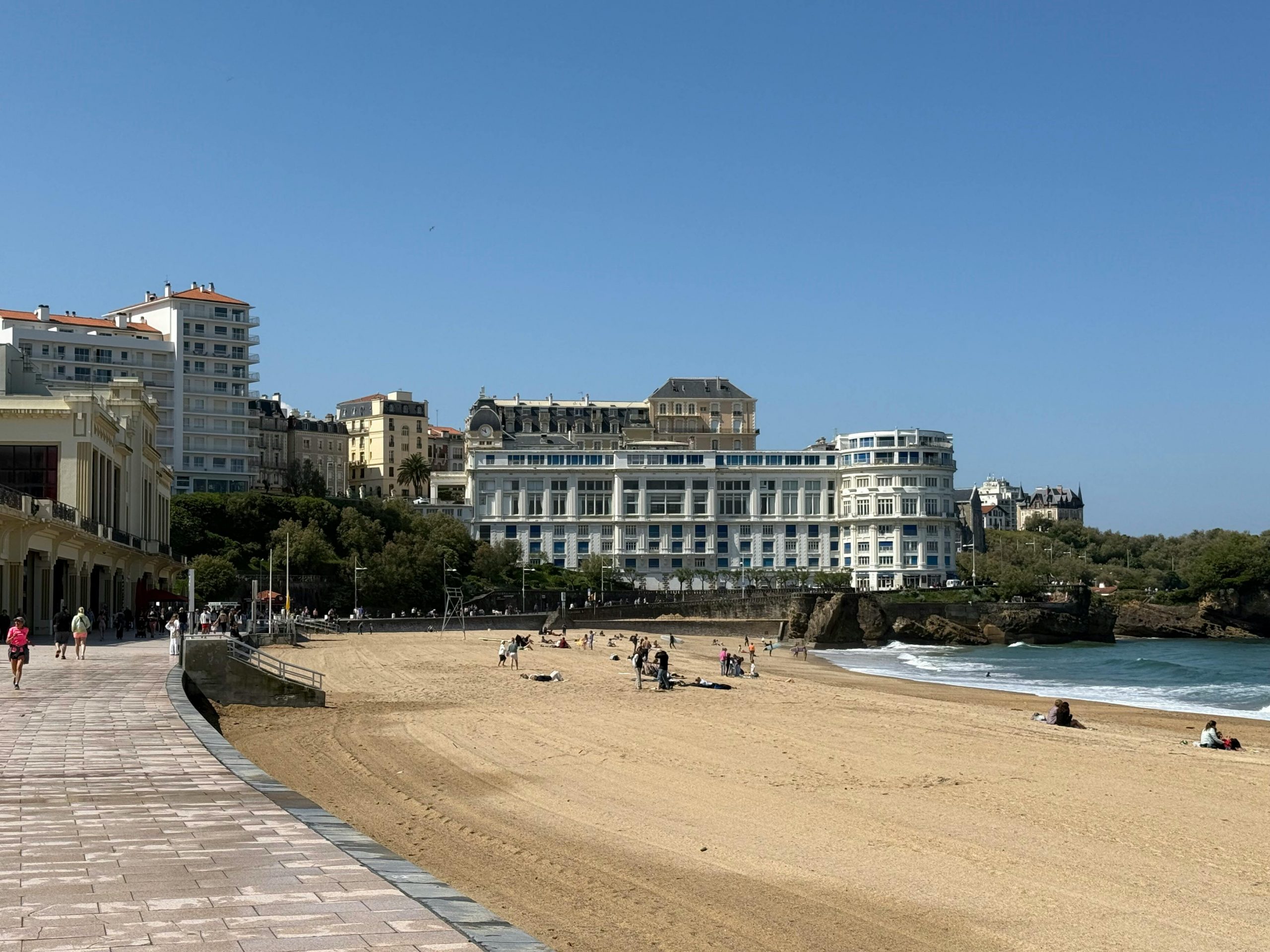 Vue panoramique de la plage et des bâtiments de Biarritz, en France, sous un ciel bleu clair.