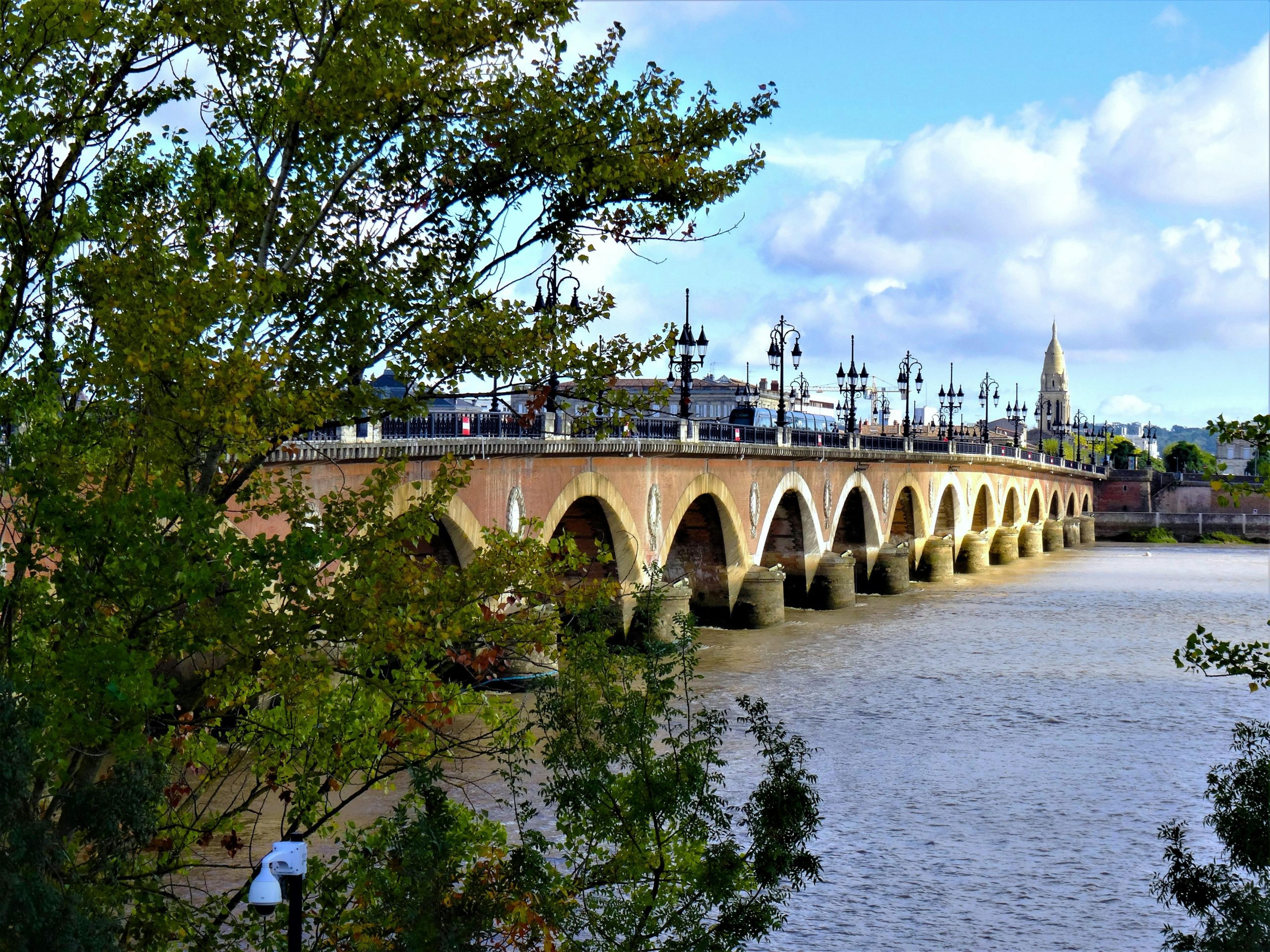 Vue panoramique du pont de Pierre, pont historique enjambant la Garonne à Bordeaux, en France, sous un ciel dégagé.