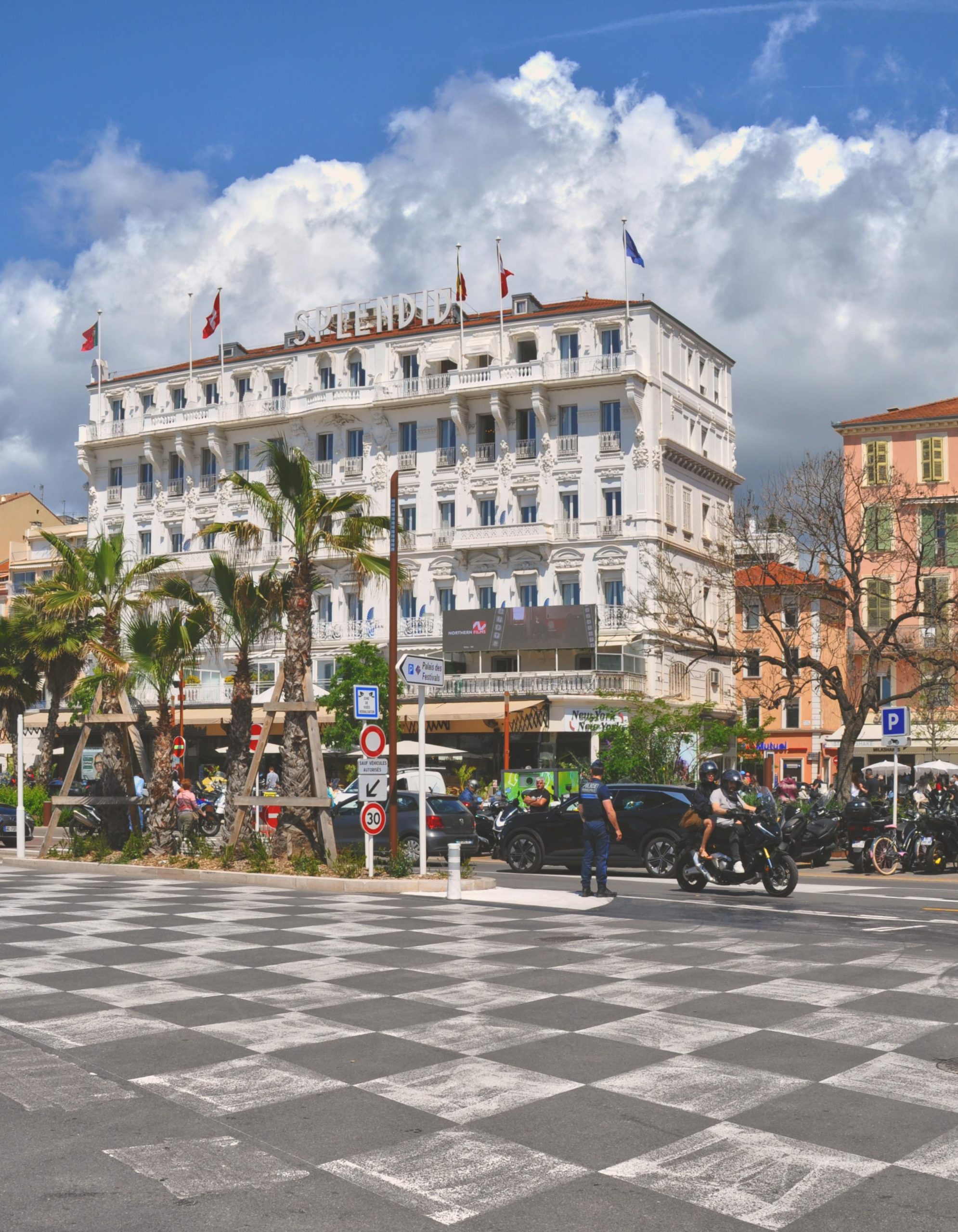 Charmante scène de rue mettant en vedette l'hôtel Salendra à Cannes, en France, avec une activité animée et des palmiers.