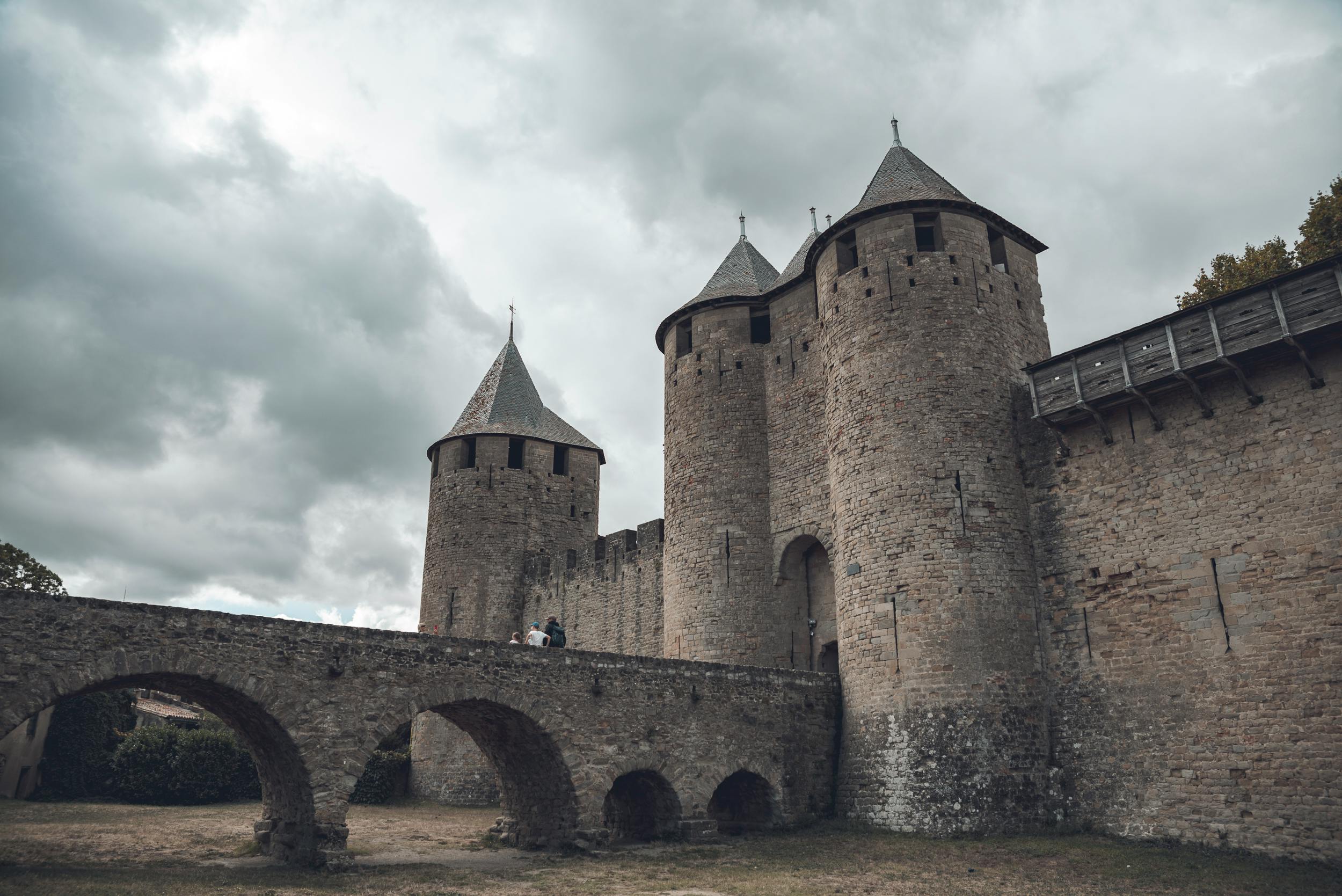 Majestueux château médiéval doté de tours de pierre et d'un pont sous un ciel nuageux.