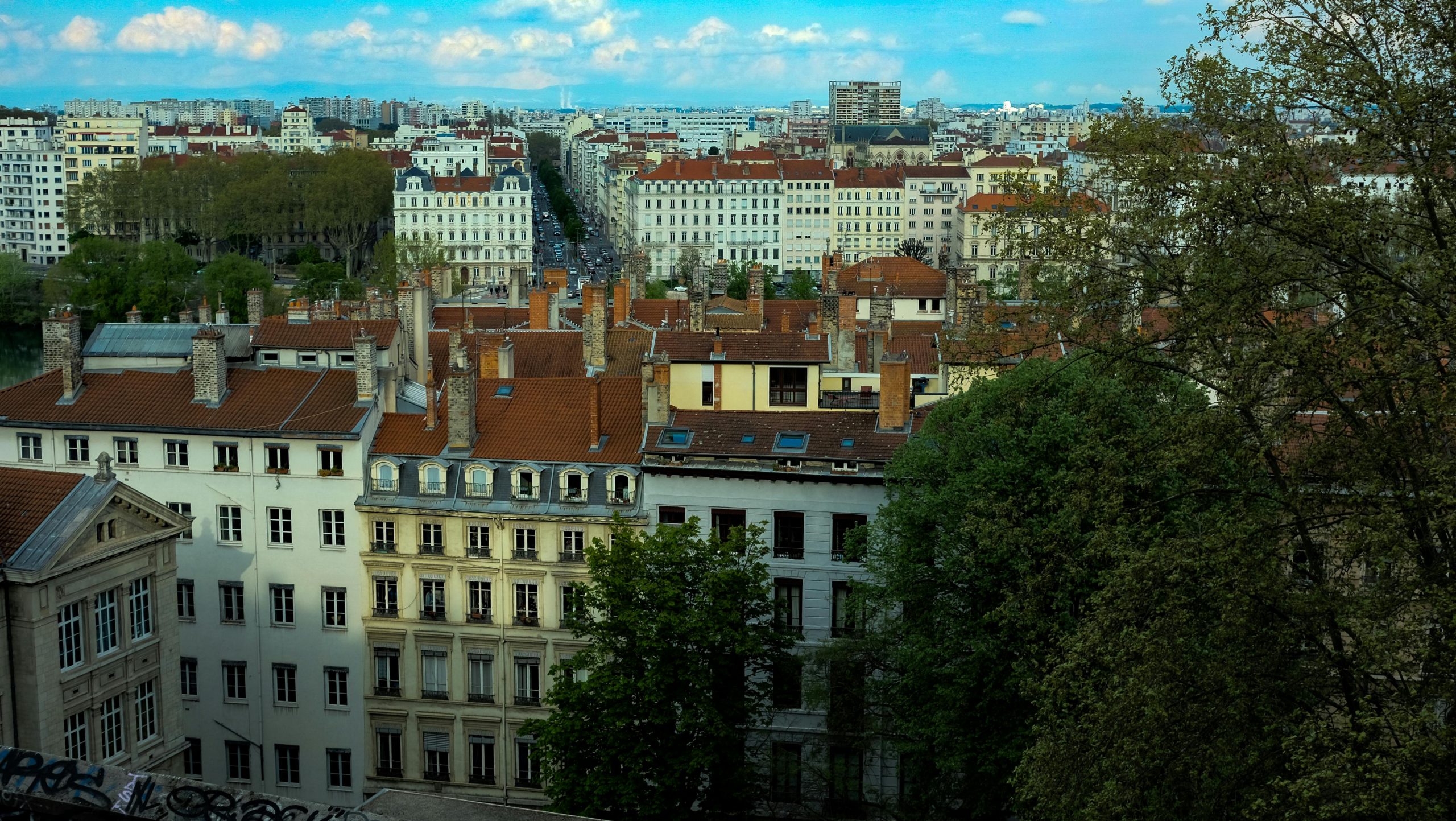 Vue imprenable sur l'architecture historique de Lyon et ses toits rouges avec en toile de fond le paysage urbain.