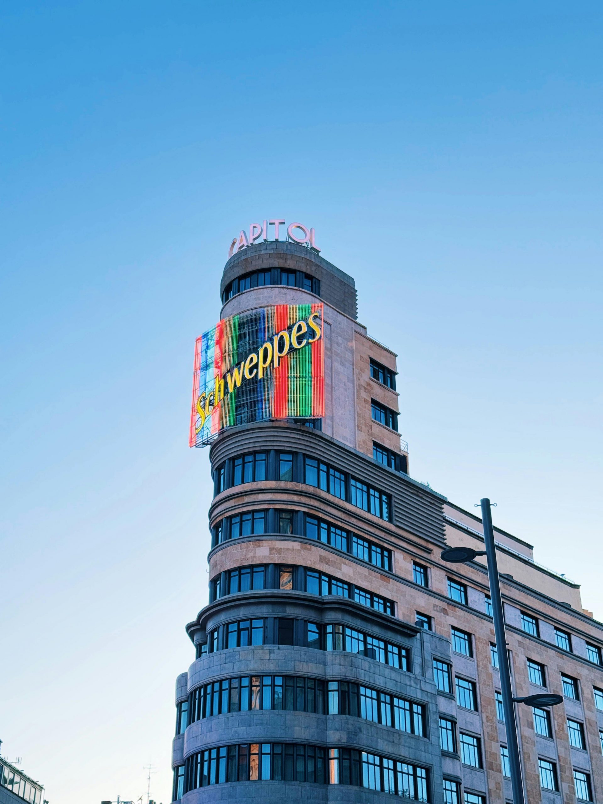 Vue du Capitole avec le panneau Schweppes à Madrid sous un ciel bleu clair.