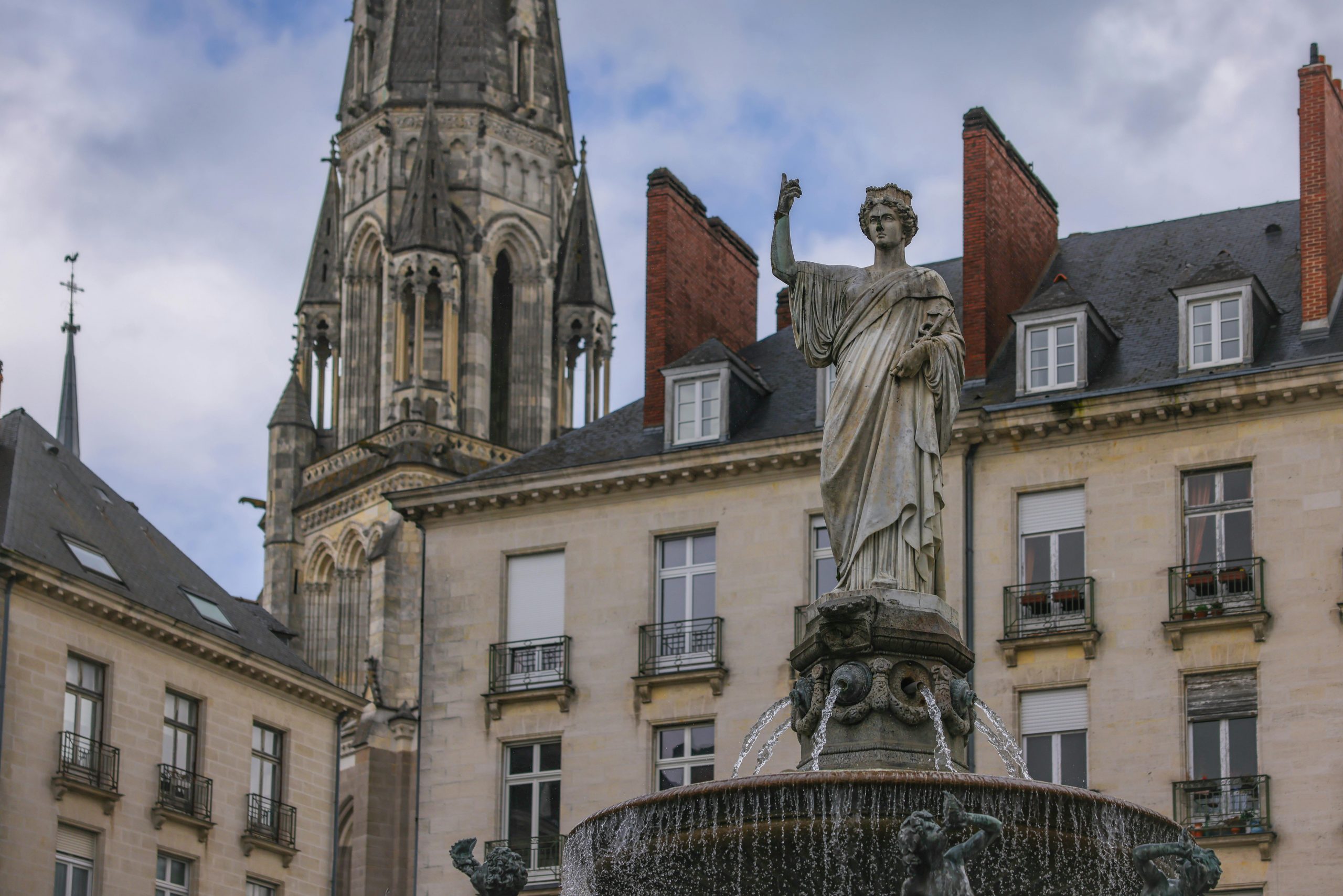 Fontaine élégante et façade d'église historique à Nantes, France.
