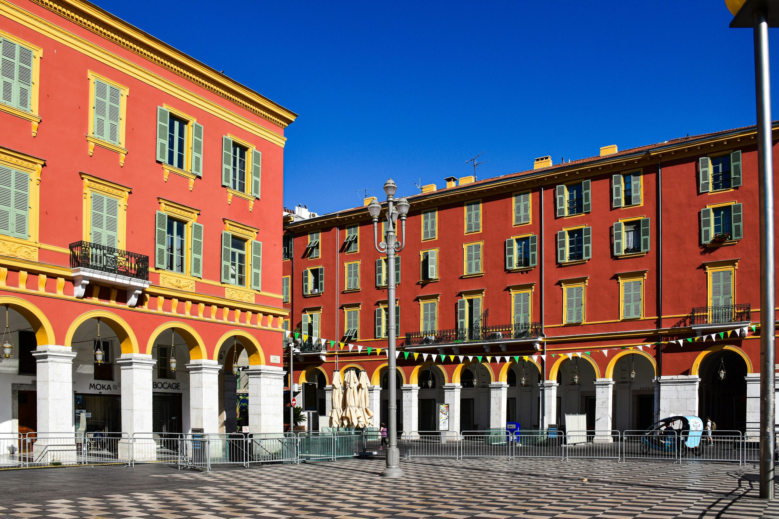 Bâtiments rouges et jaunes vifs sur une place ensoleillée à Nice, Provence-Alpes-Côte d'Azur, France.