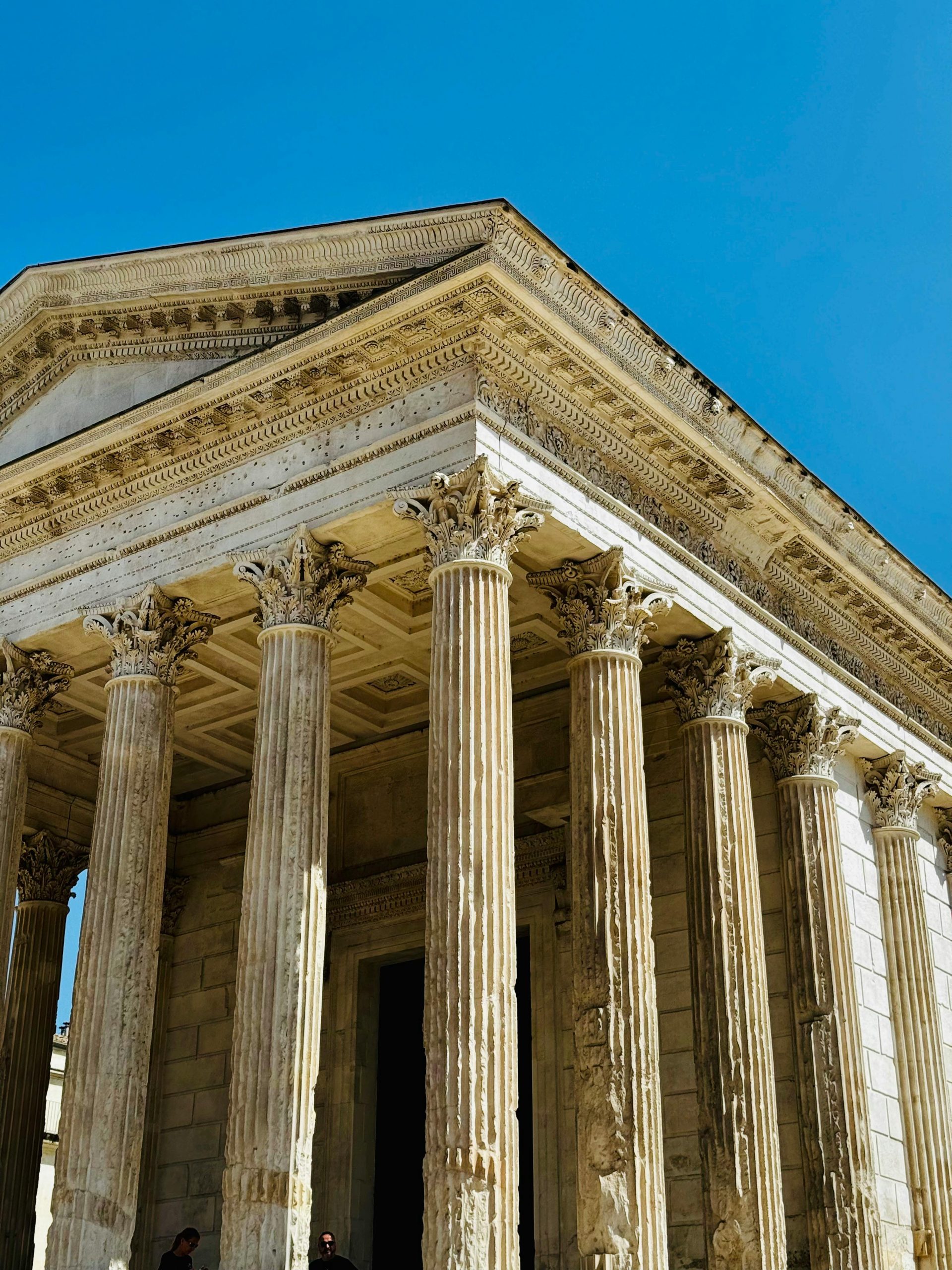 Gros plan sur la façade du Capitole à Toulouse, ornée de sculptures classiques et de drapeaux.