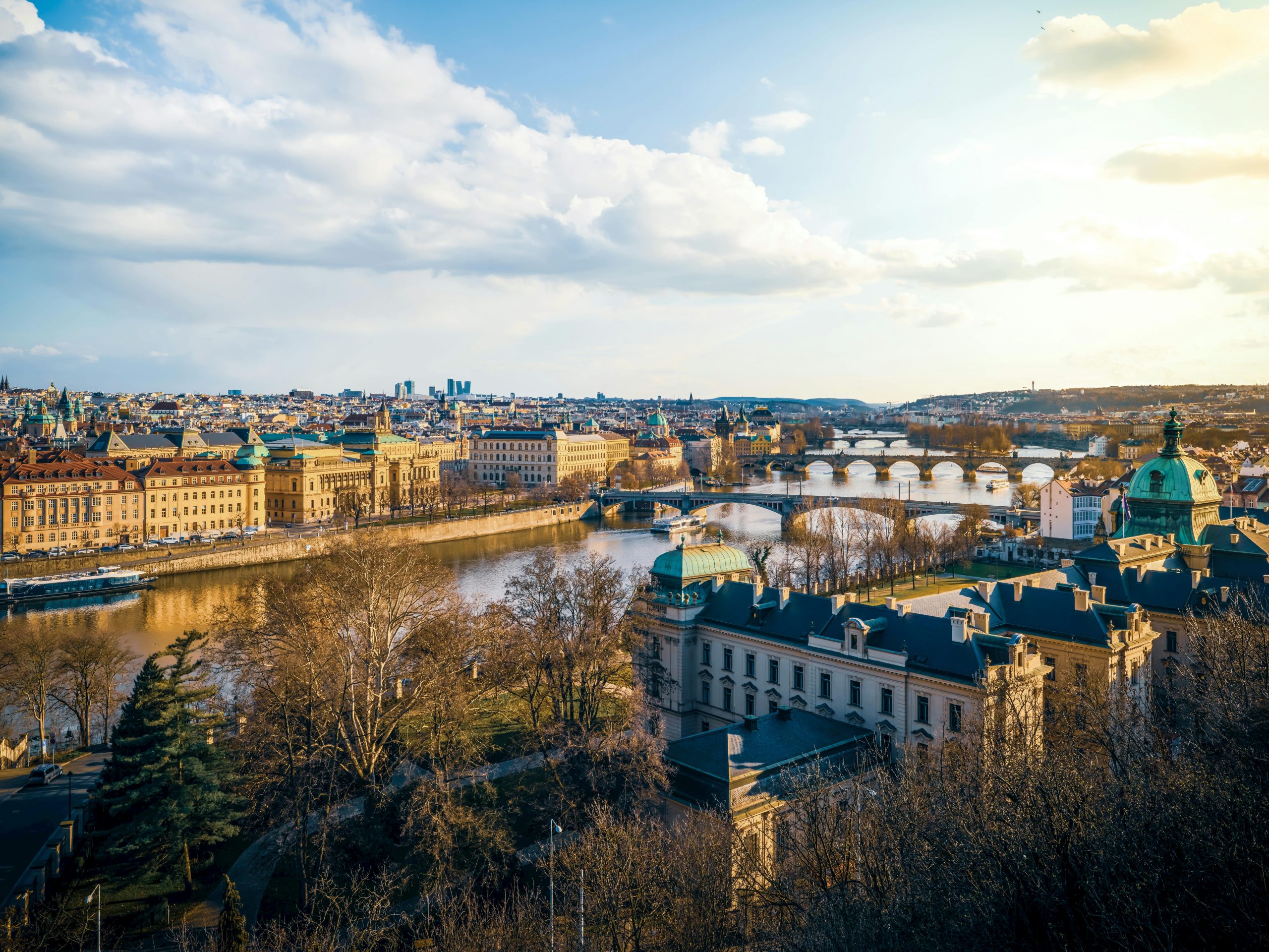 Une magnifique vue aérienne de Prague mettant en valeur ses ponts emblématiques et son fleuve au coucher du soleil.