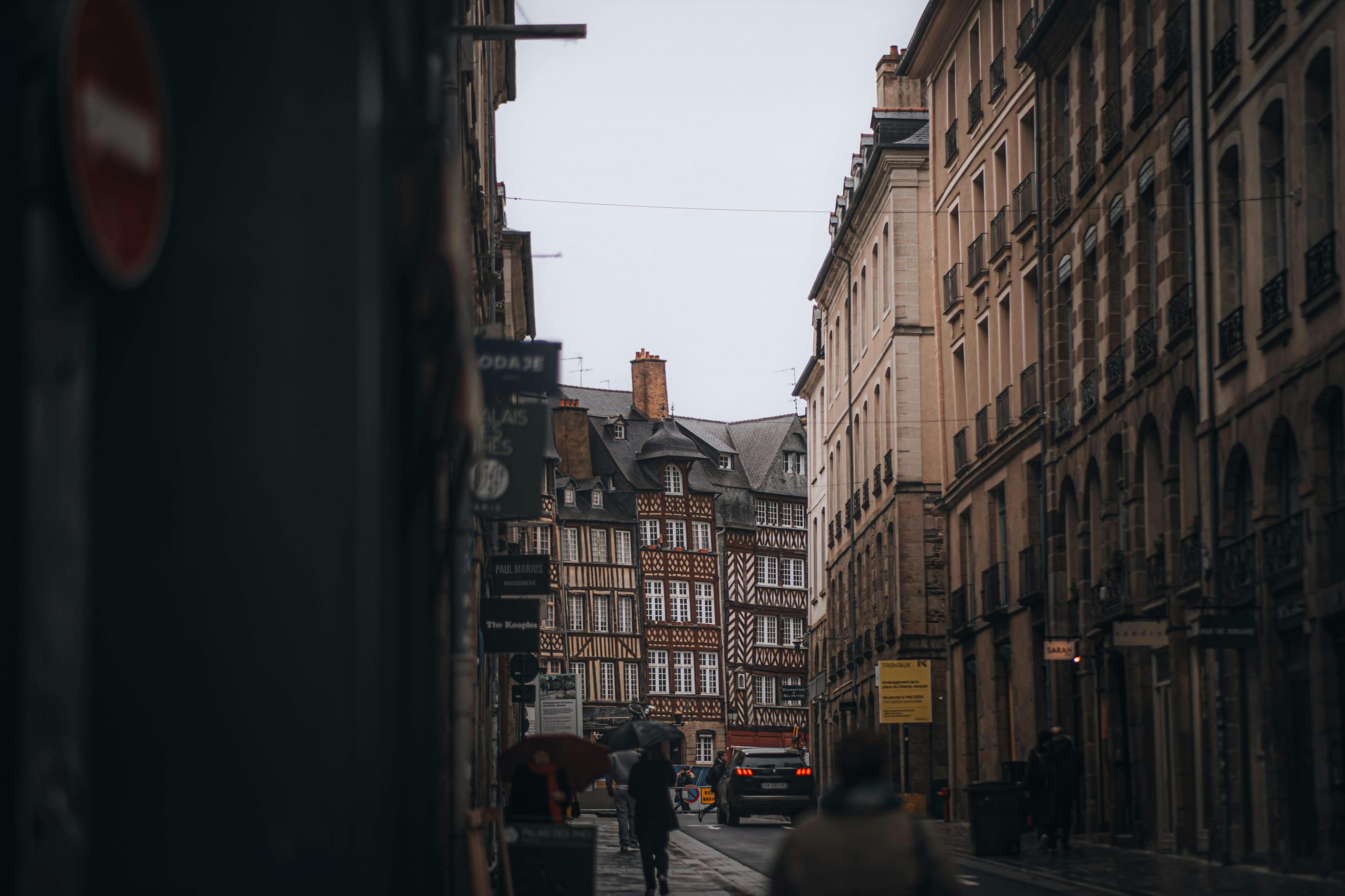 Une vue pittoresque de la rue de Rennes, présentant l'architecture traditionnelle à colombages par temps nuageux.