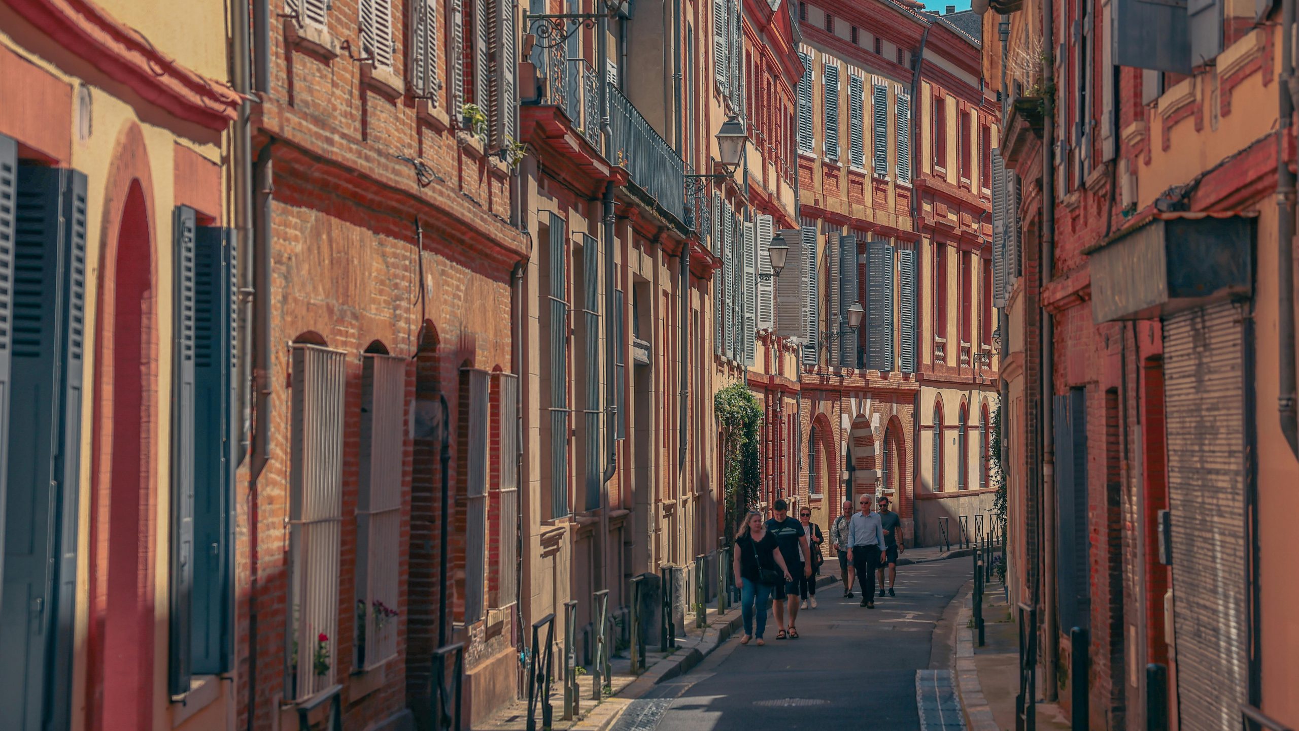 Rue pittoresque de Toulouse présentant une architecture historique et des piétons sous un ciel ensoleillé.